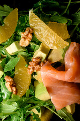 Fresh mixed salad of green leaves, red fish, orange and walnuts