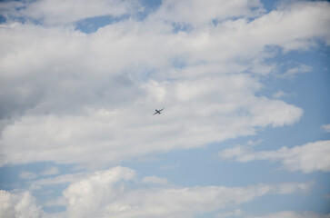 Airplane flying in the blue sky with white clouds at sunny day