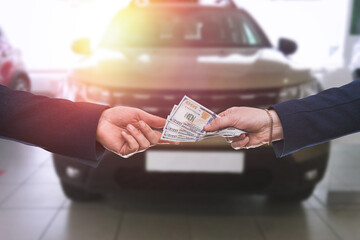 man gives dollar cash to dealer man when buying a car at modern showroom