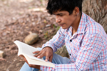 lifestyle in nature. young latin man reading a book outdoors