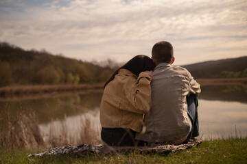 A boy and a girl embracing by the lake shore, depicting teenage relationships and friendship. Their first date in nature, enjoying the park's natural beauty. Valentine's Day