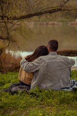 A young man embraces a girl, both facing the lake, enjoying nature and active leisure in the woods. Valentine's Day