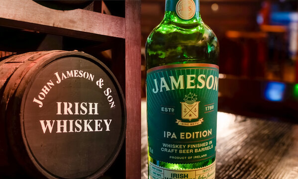 Bottle of Irish triple distilled whiskey Jameson Ipa Edition close-up on background of vintage irish whiskey barrel. Ukraine, Zhytomyr, April, 22, 2024