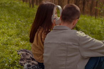 Young people listen to music outdoors, enjoying tunes together. A guy and a girl spending quality...
