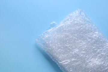 Folded transparent bubble wrap on light blue background, top view. Space for text