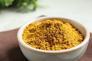 Curry powder in bowl on white table, closeup