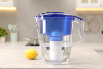 Water filter jug and lemon on light grey table in kitchen