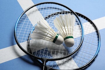 Feather badminton shuttlecocks and rackets on blue background, closeup