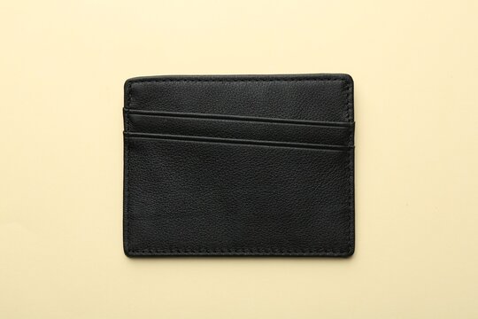 Empty leather card holder on beige background, top view