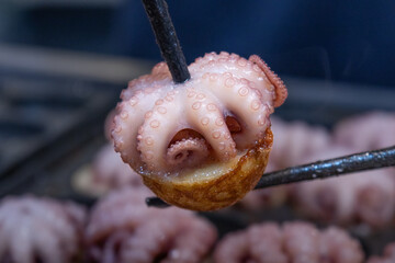 Round-shaped squid grilled mixed with flour on an electric stove.