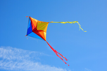 A colorful kite soaring high in the bright blue sky.