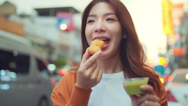 Happy young tourist Asian woman enjoy and fun traditional asian street food at Bangkok Chinatown, Female shopping and eating street food on summer holiday vacation