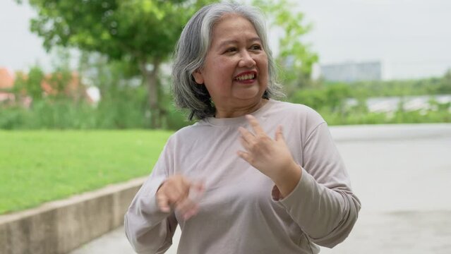 Senior woman jogging in outdoor stadium. Elderly female person is happy about cardio for health and wellness while walking or running in summer. Concept of healthcare and active lifestyle for healthy
