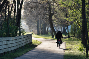 Man in silhouette in morning sunlight on bicycle trail