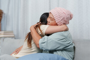 Hugs and joy abound as elder in knitted cap and younger female share affectionate embrace on sofa....