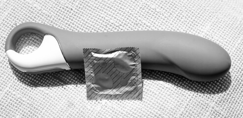 A dildo with a condom, an intimate toy for women.
Vibrator for pleasure.
Black and white photo - obrazy, fototapety, plakaty