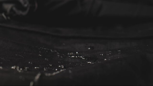 Water dripping onto waterproof fabric. Water jet on water resistant jacket. drops of water on water-repellent clothing