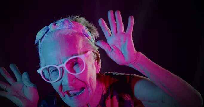 Slow motion : An Asian woman who is an elderly woman, likes to have fun, be in a good sense of humor, showing off her excited expression to the people amidst the colorful of festival light at night.