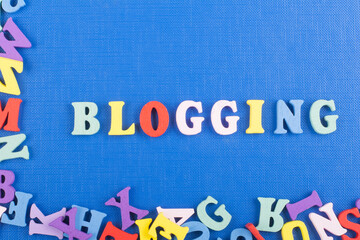 BLOGGING word on blue background composed from colorful abc alphabet block wooden letters, copy...