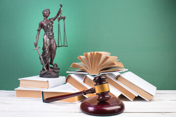 Law concept - Open law book, scales, Themis statue on table in a courtroom or law enforcement office. - 791794869