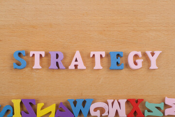 STRATEGY word on wooden background composed from colorful abc alphabet block wooden letters, copy...