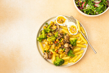 Delicious breakfast, pasta with fried mushrooms and broccoli, green peas and corn, fresh mix salad...