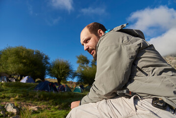 Portrait of a latin male hiker sitting relaxed at a mountain campsite in the Los Gigantes area,...