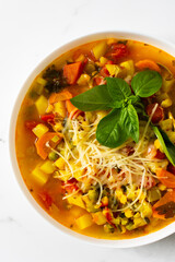 Minestrone soup from zucchini and tomato, onion and carrots, corn and peas with parsley, bowl of...