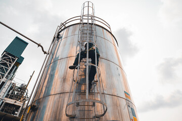 Top view male worker climbs up the ladder inspection stainless tank work at height