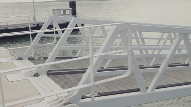 A contemporary ferry pier, showcasing white metal framework against a calm water backdrop, symbolizing modern public transportation infrastructure.