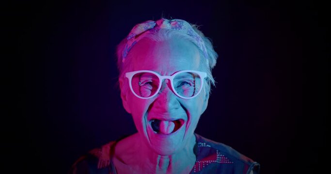 Slow motion : An Asian women who is an elderly woman, likes to have fun, be in a good sense of humor, showing off her laughing to the people amidst the colorful of festival light. 