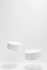 Set of two tilt round white podiums mockup for cosmetic products, levitate in hard light, shadow on white background. Scene for presentation products, gifts, advertising, design in modern style.