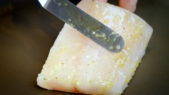 Close-up of hands putting piece of white Fish Fillet on a Pan. Food preparation, zander fillet. Slow motion 4k video.