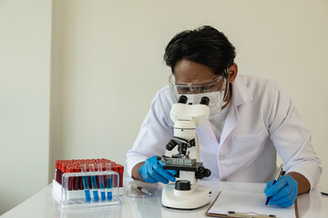 Asian scientist wearing protective mask for working in a laboratory, test tubes, microscope in a chemistry lab. development and research