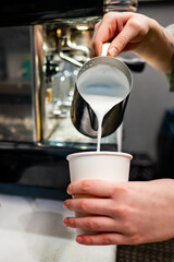 Skilled barista pouring steamed milk into a coffee cup, creating a warm, delicious beverage. Perfect for coffee lovers and café culture