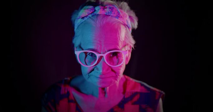 Slow motion : An Asian woman who is an elderly woman, likes to have fun, be in a good sense of humor, showing off her smiling face pose to the people amidst the colorful of festival light. 