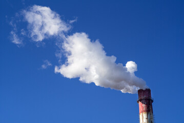 Smoke and steam billow from the chimney against a blue sky