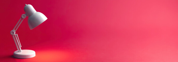 White table lamp on a red background, copy space.