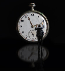 Bussiness man in suit holding clock hand on reflection surface. Stop time concept, deadline - 791826234