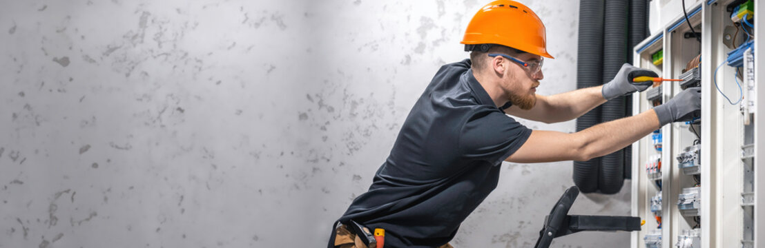 Electrician working in switchboard with electrical connection cable, copy space.