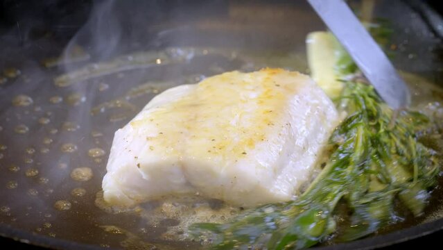 A zander fillet frying in a frying pan. Cooking fish in the hot oil. Slow motion video. 100fps