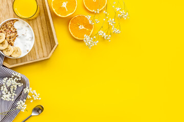 Bright breakfast with granola and orange juice on yellow background top view mockup