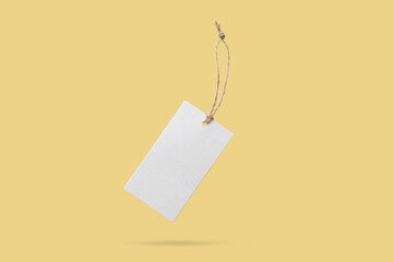 Blank price tag tied with string float on yellow background - 791831247