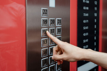 Selective focus on woman forefinger pressing on button in the passenger elevator