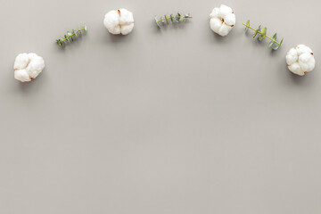 Flowers border with green eucalyptus branches and dry cotton flowers on grey background top view copy space