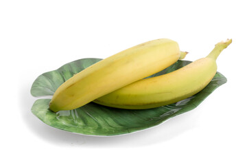 two ripe yellow bananas on a green leaf shaped plate isolated on a white background