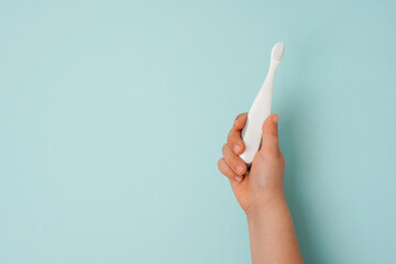 toothbrush in a child's hand on a blue background with space for text