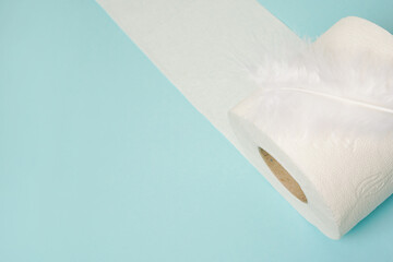 Roll of toilet paper with white feather on blue background with space for text