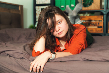 Portrait of a young beautiful woman on the bed in the bedroom.