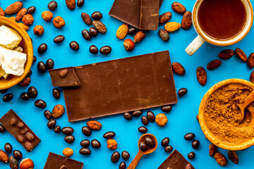 Cook homemade chocolate with bars, nuts, coffee beans on blue background top view